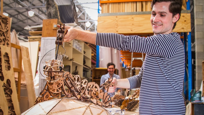 Nicholas Paine holding one of the wooden laser cut puppets the company uses.