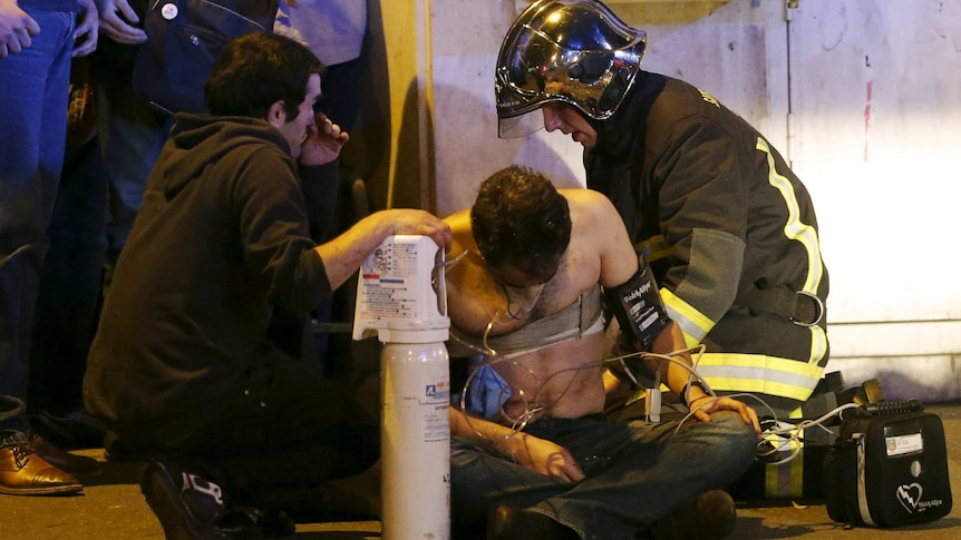 Fire brigade members aid an injured man near the Bataclan concert hall.