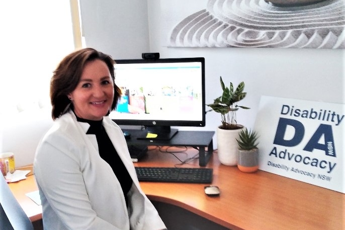 A woman in her office smiling looking at the camera.