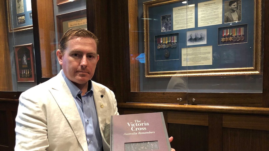 man holding a book about the victoria cross