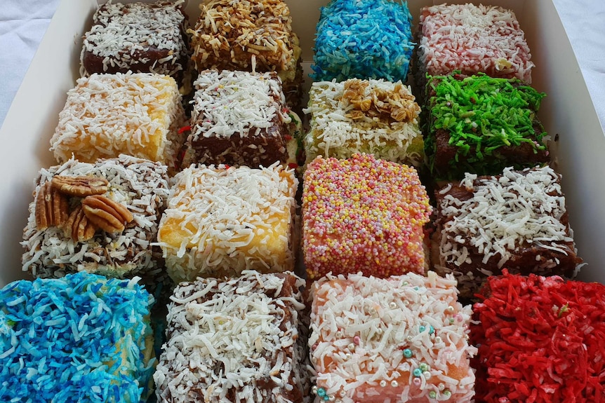 Square, coloured lamingtons in a box for a story about lamington's history and baking tips.