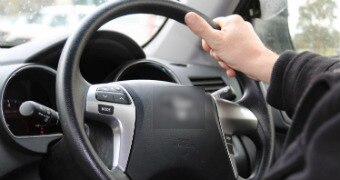 A hand on the steering wheel of a car
