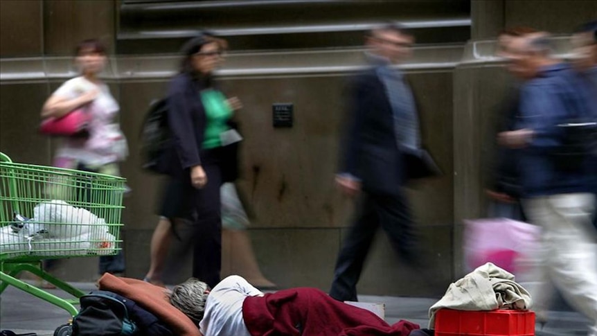 A homeless man sleeps next to his belongings