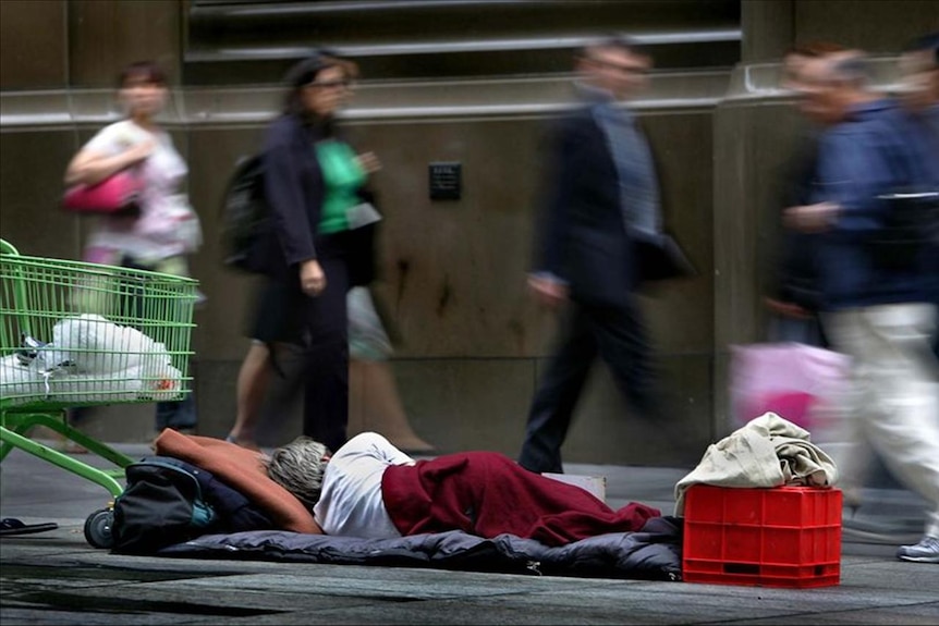 A homeless man sleeps next to his belongings