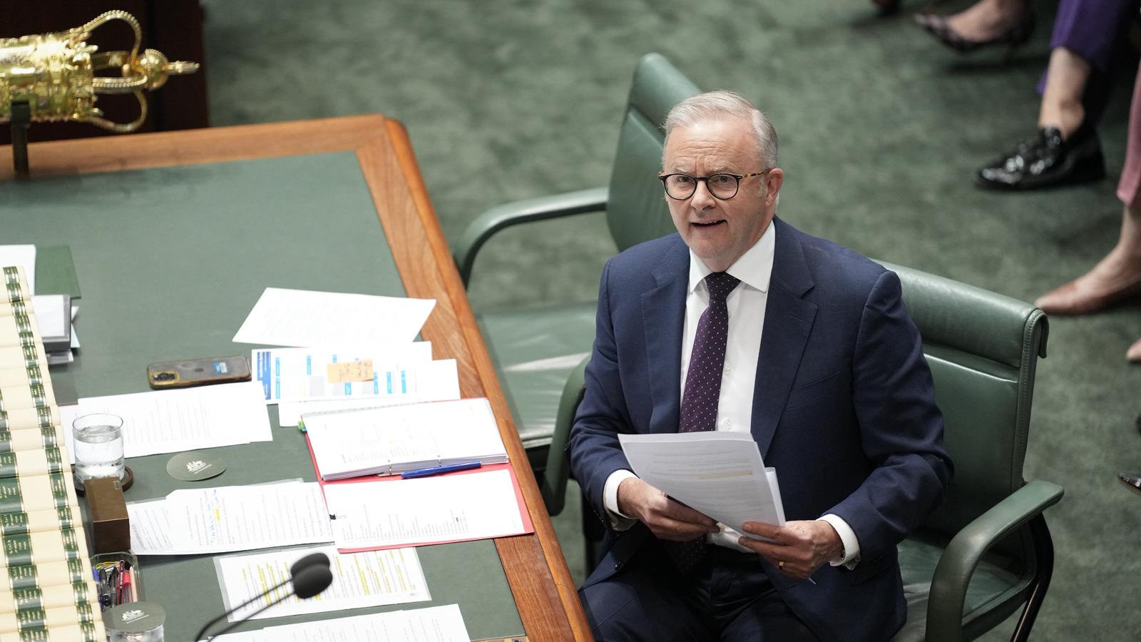 Anthony Albanese sits and holds a piece of paper.