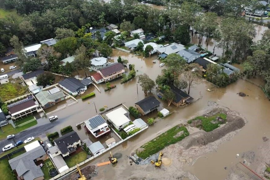 Drone photo of houses and streets becoming inundated with brown floodwaters