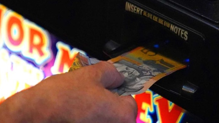 a 50 dollar note being put into a poker machine