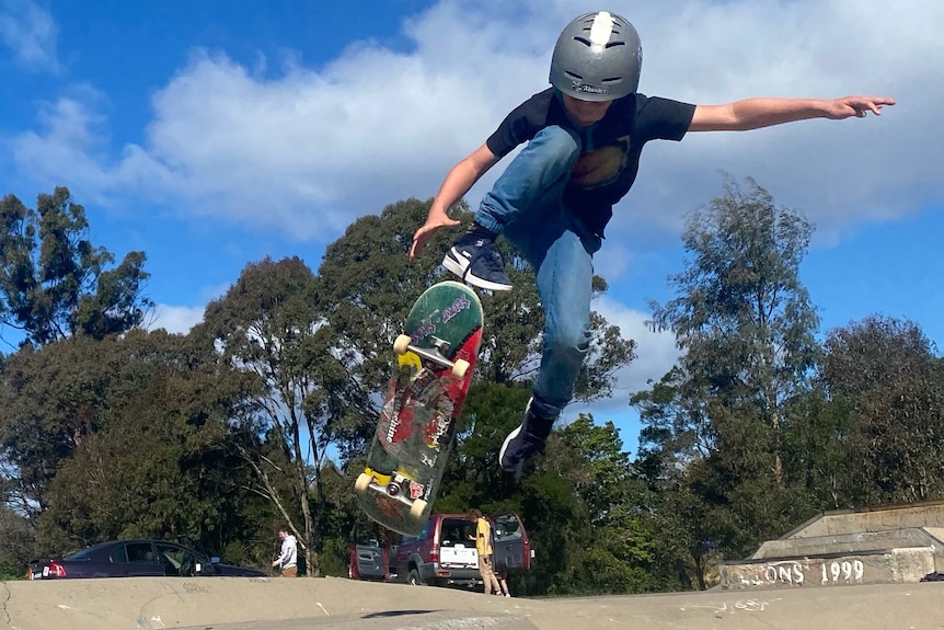 A young boy with a skateboard in the air.