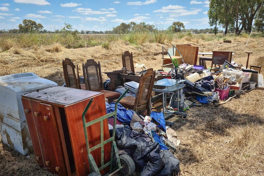 Ruined furniture and belongings are piled up outside in a paddock
