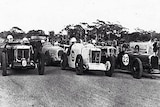 A black and white photograph of 1930s racing cars with their drivers waiting to start.