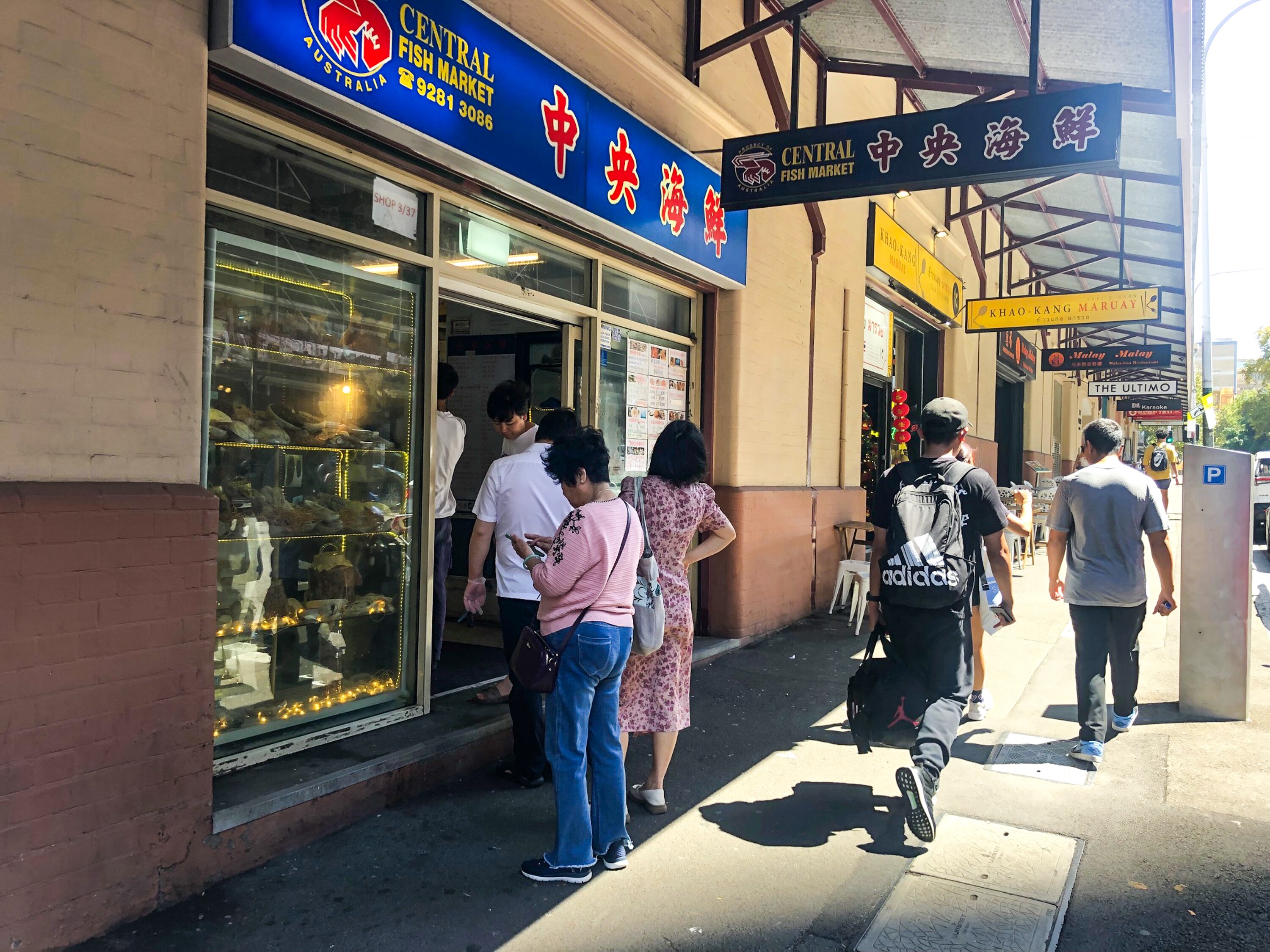 La gente se encuentra en una línea fuera de una tienda del mercado de pescado en Chinatown.