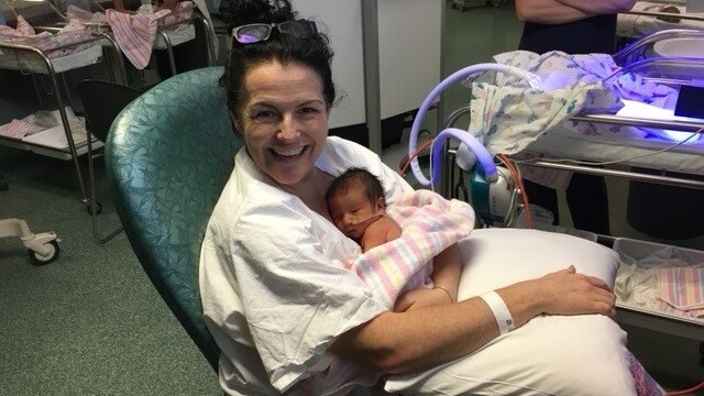 A woman holds her new born baby in a hospital ward