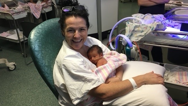 A woman holds her new born baby in a hospital ward