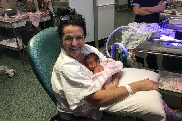 A woman holds her new born baby in a hospital ward