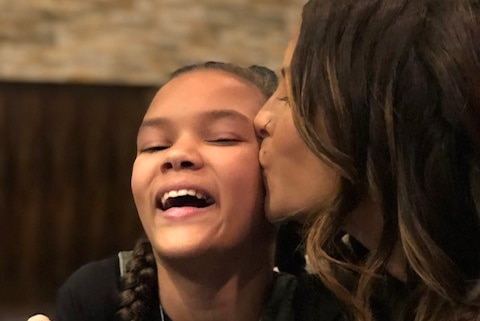 A woman kisses a young girl on the cheek.