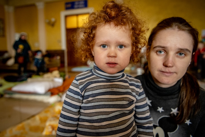 A little girl with red curly hair looks at the camera 