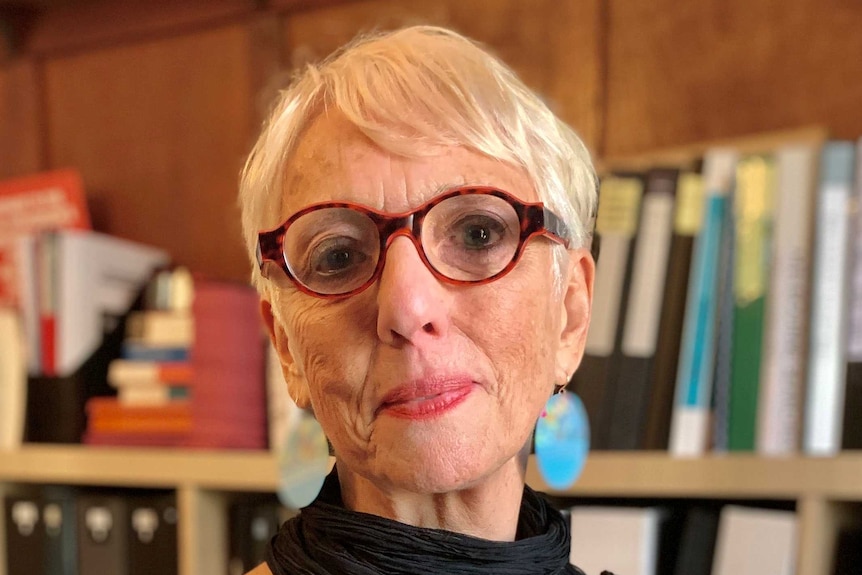 A portrait of lawyer Judy Courtin in a room lined with books.