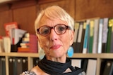 A portrait of lawyer Judy Courtin in a room lined with books.