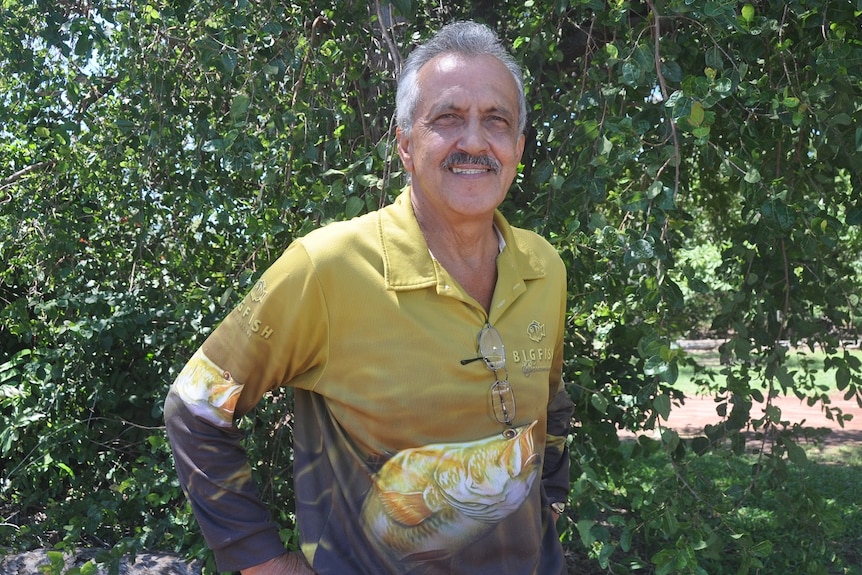 A fishing shop owner smiling in the sun.