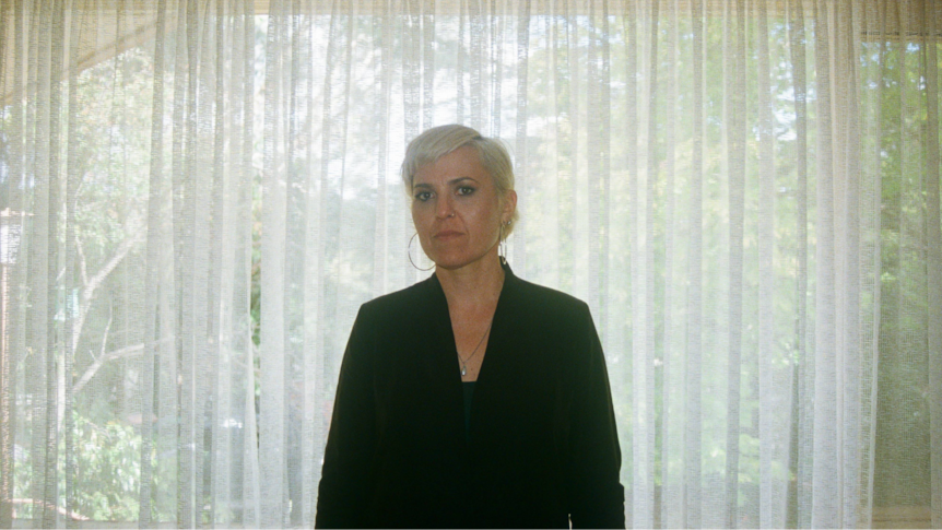 Australian musician Liz Stringer stands against lace curtains