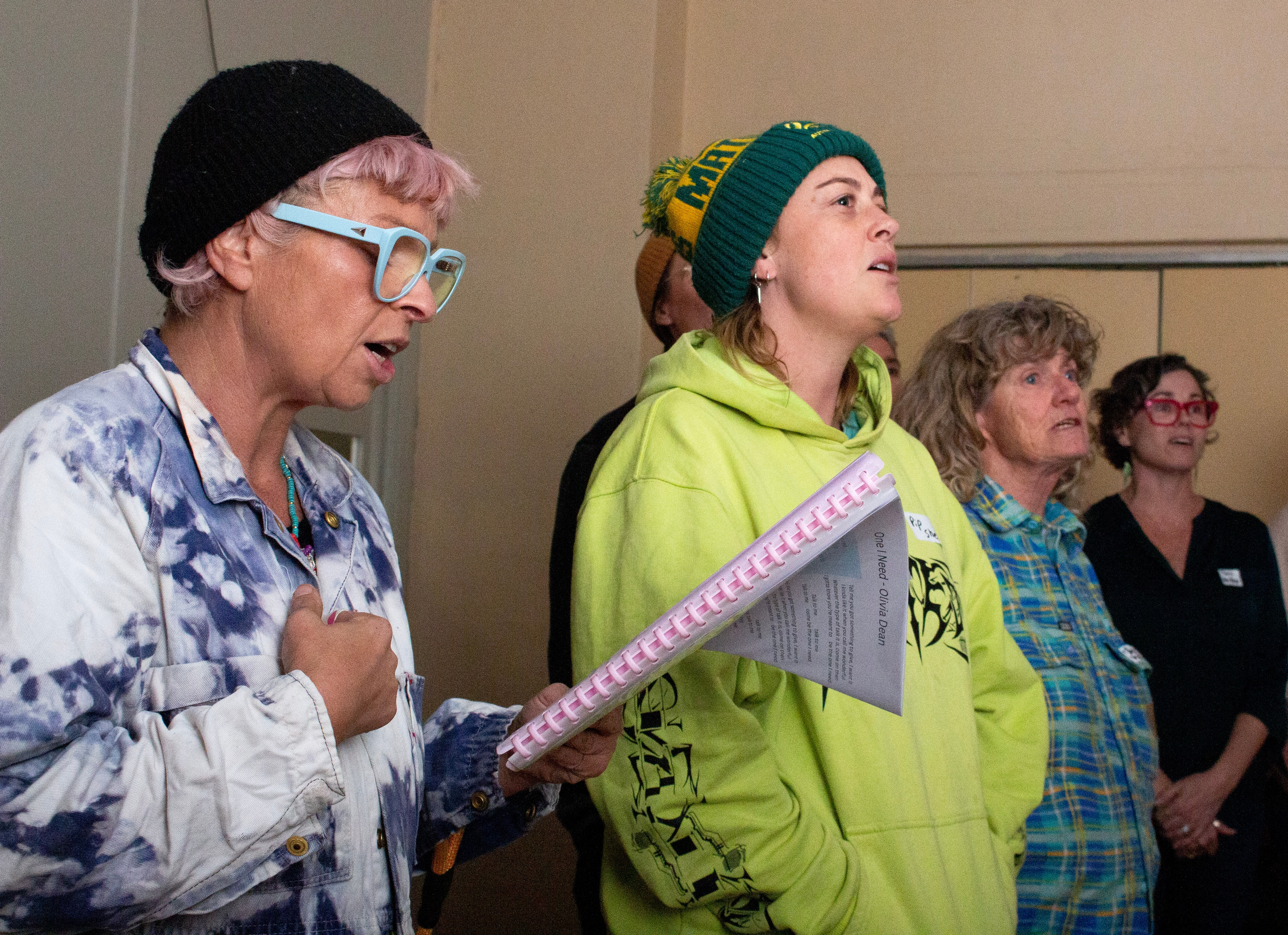 Side view of a group of people singing in a room. 