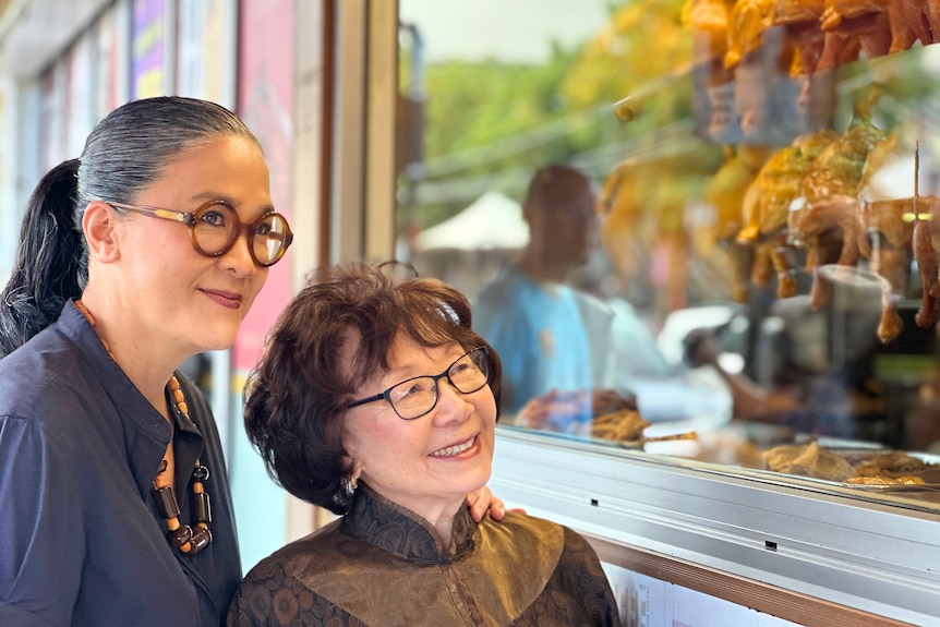 Kylie Kwong and her mum look at roast ducks in a shop window