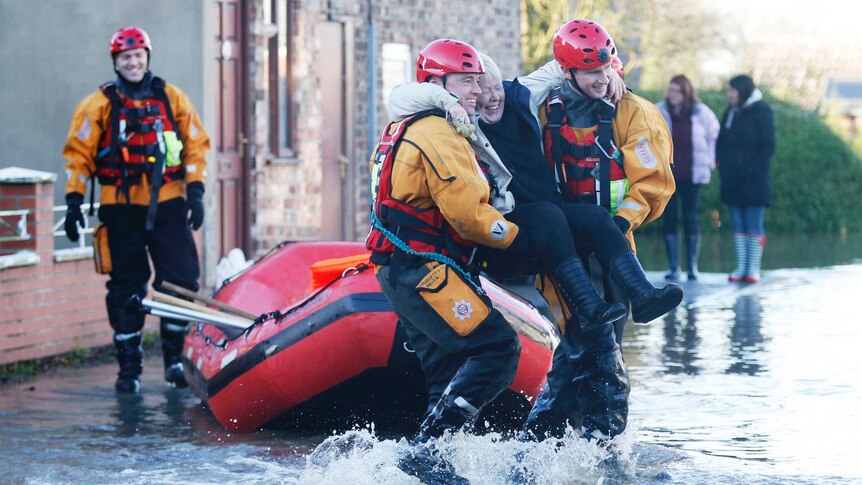 Members of the emergency services rescue a woman from a flooded street in northern England.