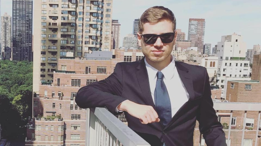 A man in sunglasses poses in front of the skyline