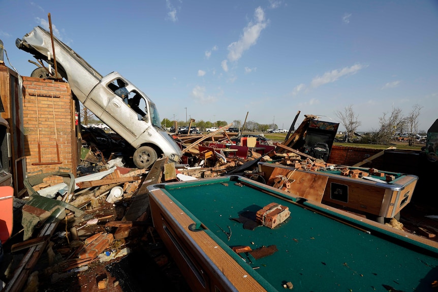 A ute rests on to of a restaurant cooler behind a billards table, after a tornado ripped through Mississippi.