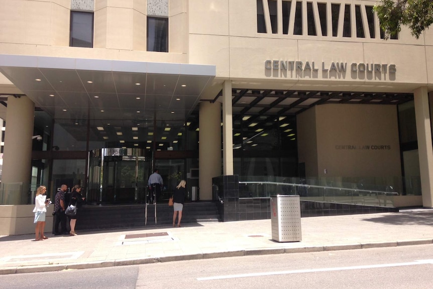 A wide shot of the front of the Central Law Courts in Perth with a handful of people standing at the steps outside.