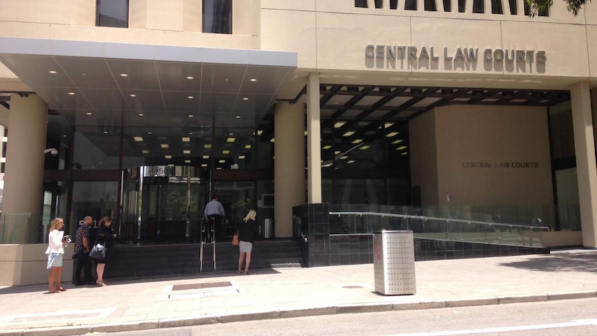 A wide shot of the front of the Central Law Courts in Perth with a handful of people standing at the steps outside.