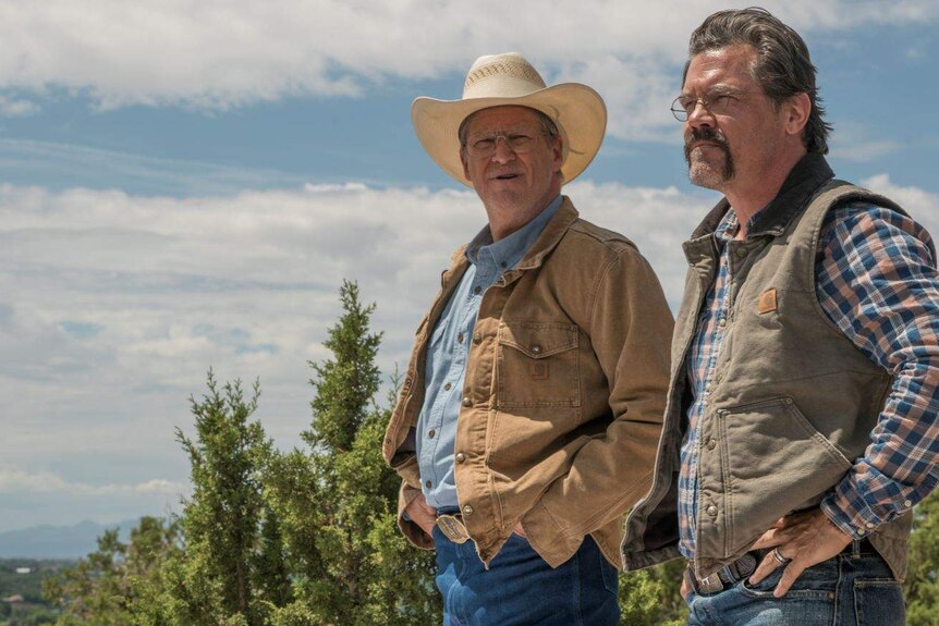 Still colour mid-shot image from 2017 film Only The Brave of Jeff Brides and Josh Brolin standing in the sun amongst scrubland.