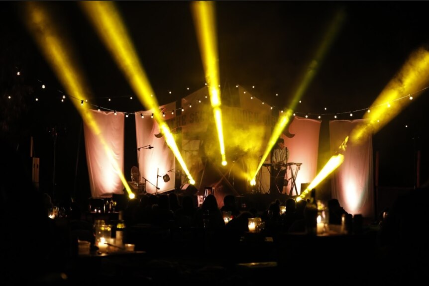 dark stage with lights and a musician