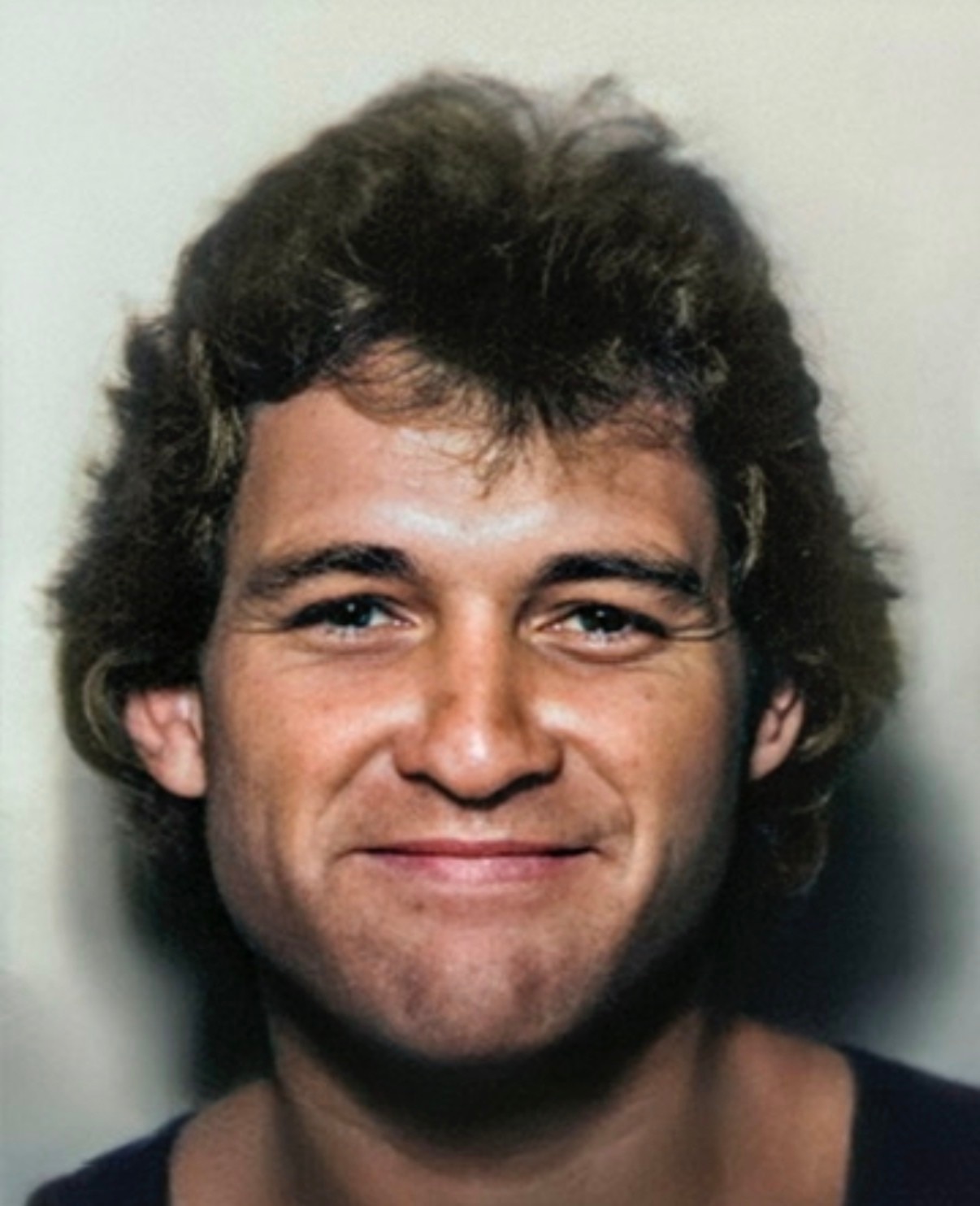 A headshot of a smiling man with dark hair.