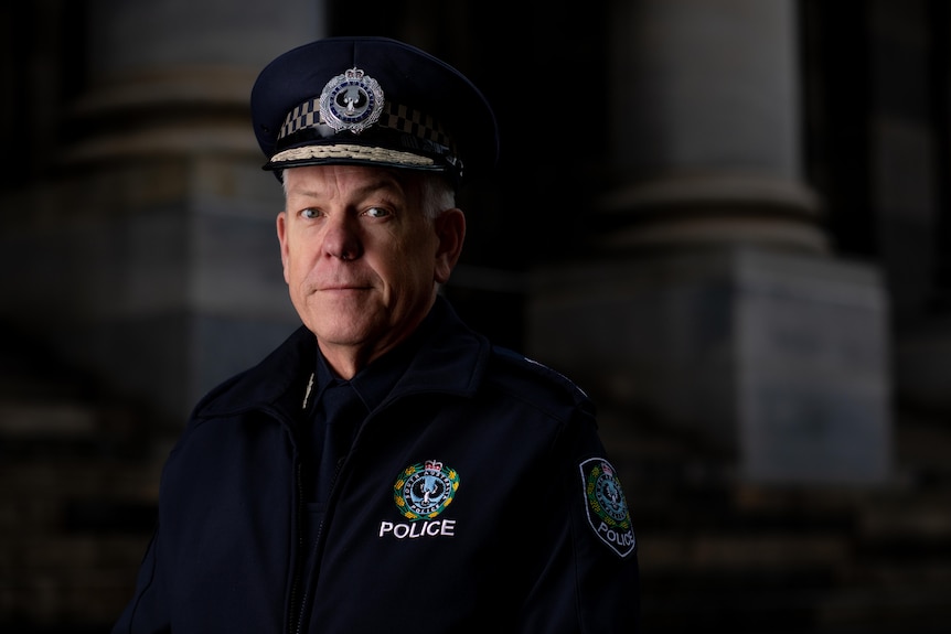 A police officer wearing a peaked hat in a dark photo