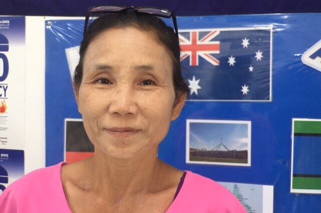 Karen refugee Cherry smiles in front of a poster showing the Australian flag.