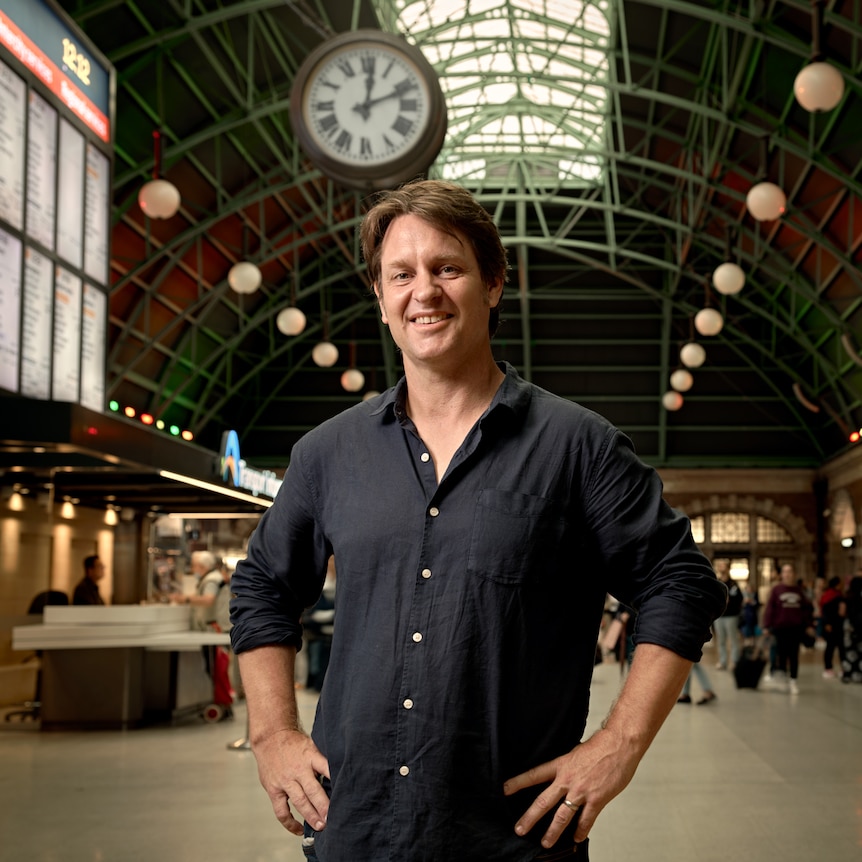 Craig Reucassel on a busy Central Station concourse, with commuters rushing past.