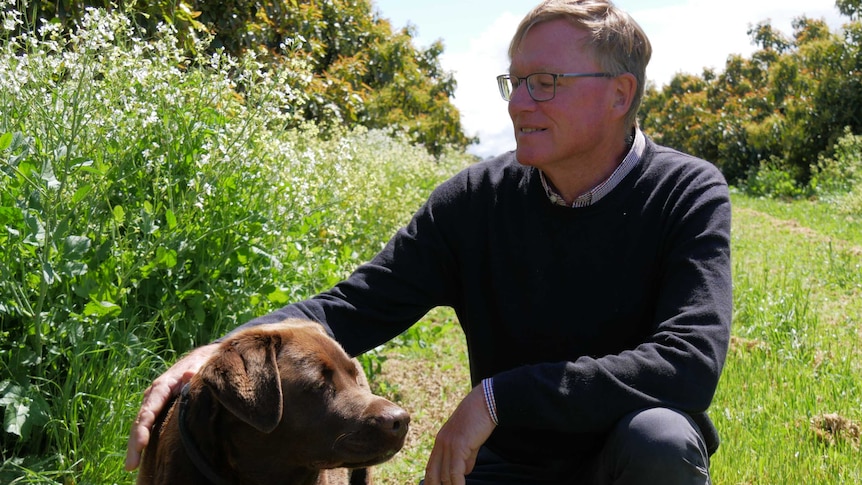 Doug Pow standing on his farm in Manjimup with his dog.