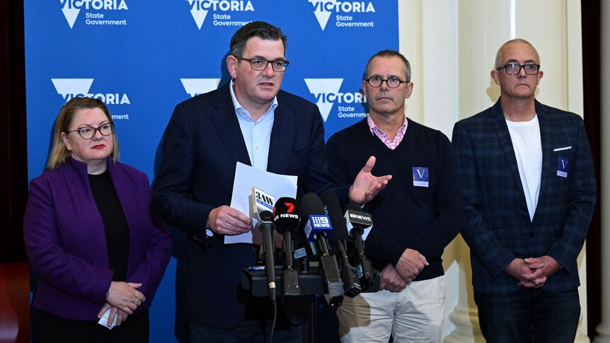 Victorian Premier makes an announcement in front, flanked by a woman and two men.
