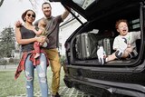 A basketballer, his wife and child are next to a car, while another other child sits in the boot.
