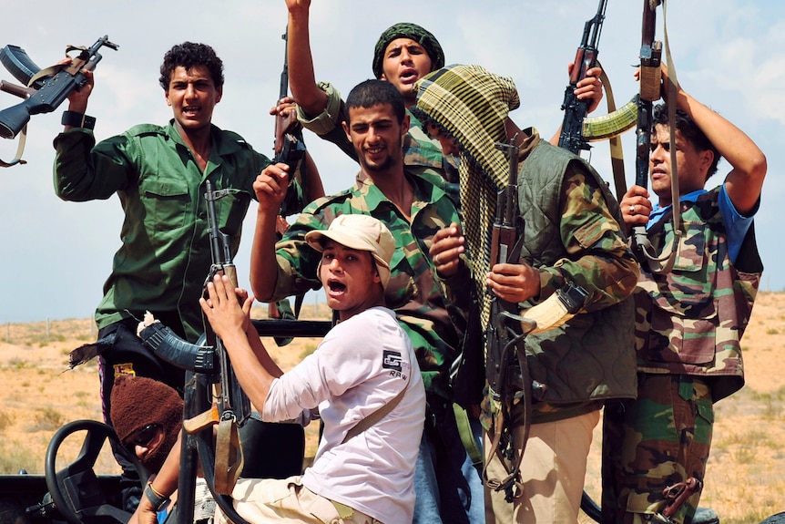 Anti-Gaddafi fighters hold up the weapons that they say were seized from houses near Sirte