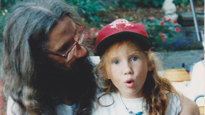 A man with a young girl with red hair in a cap