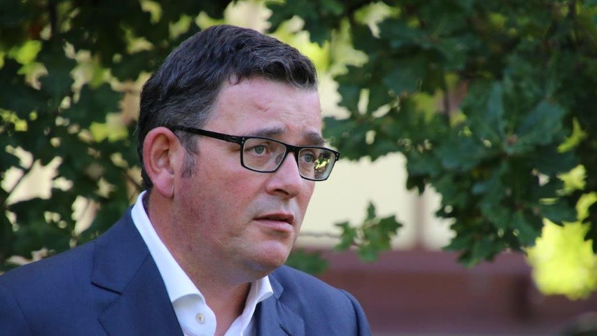 Victorian Premier Daniel Andrews speaks to media in front of a green, leafy backdrop