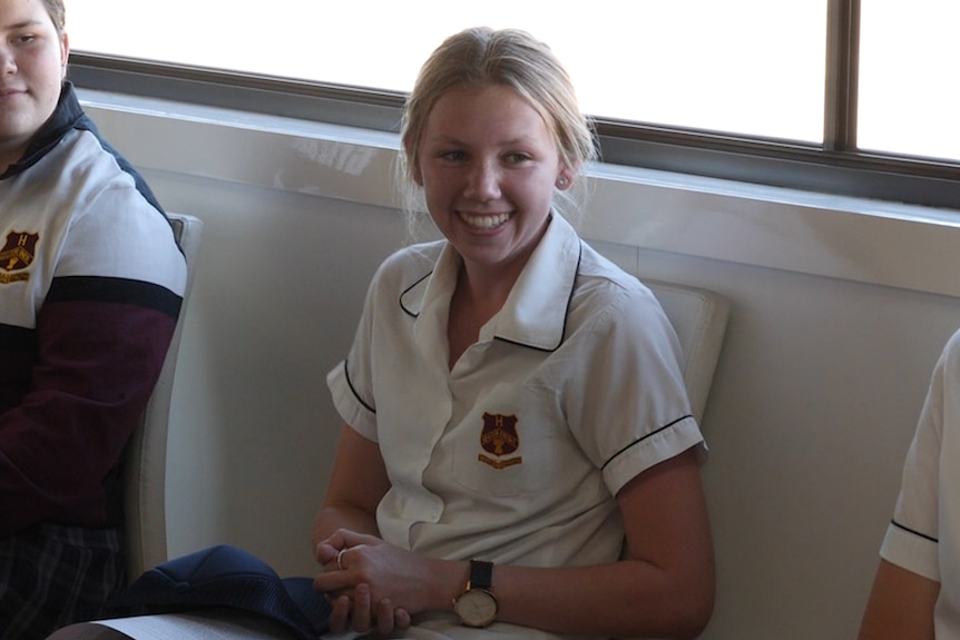 A young female student smiles at a room full of people