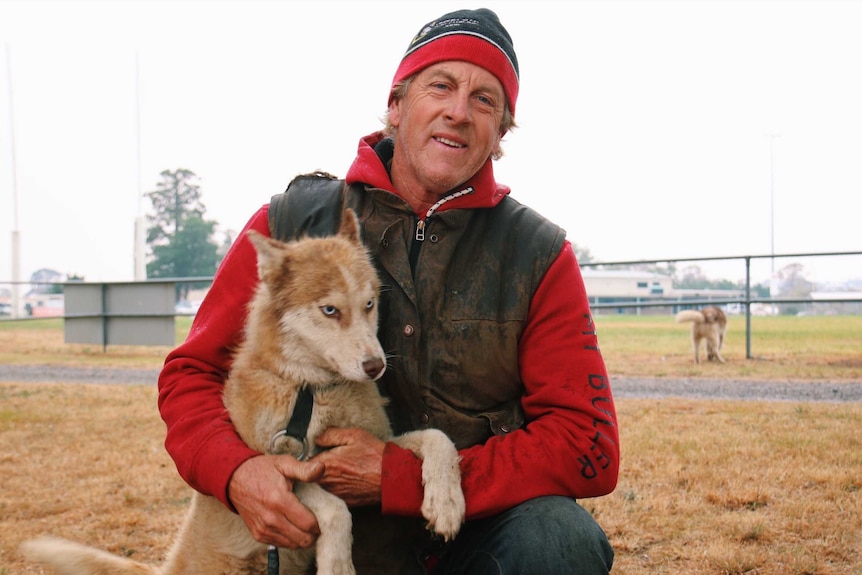 Brett Hadden, wearing a beanie, holds one of his husky dogs.