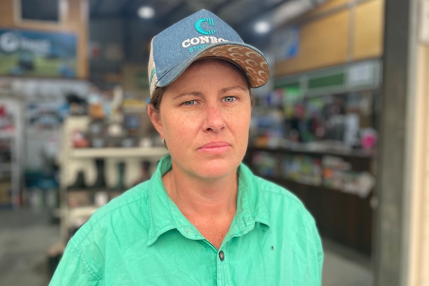 owner of Macleay Valley Rural Supplies Loretta Simpson stands in front of her shop wearing a blue cap and a green shirt