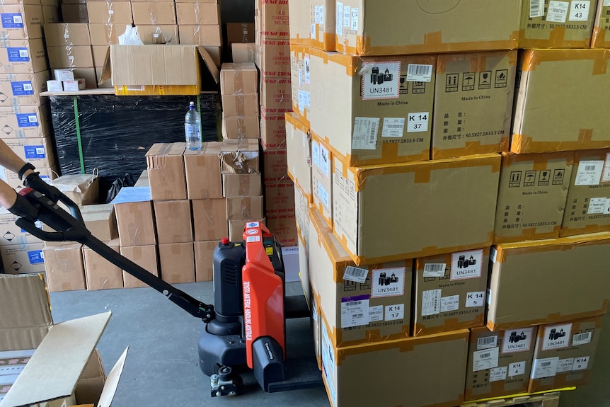 A close-up shot of a pallet of cardboard boxes being pulled by a red and black pallet jack.