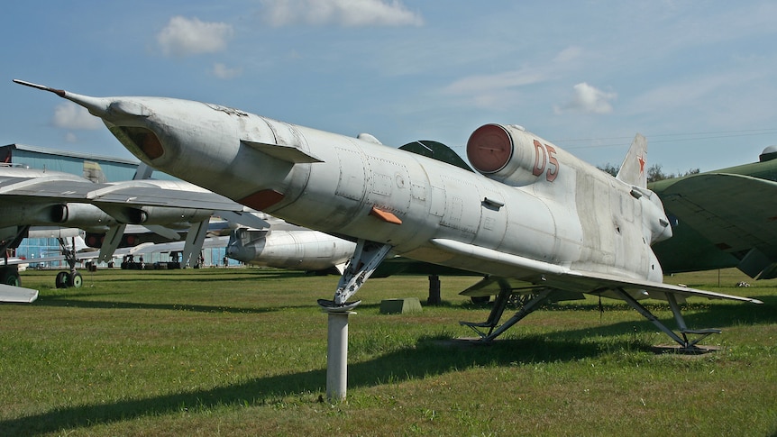 A large rocket-powered unpiloted drone sitting in a field.