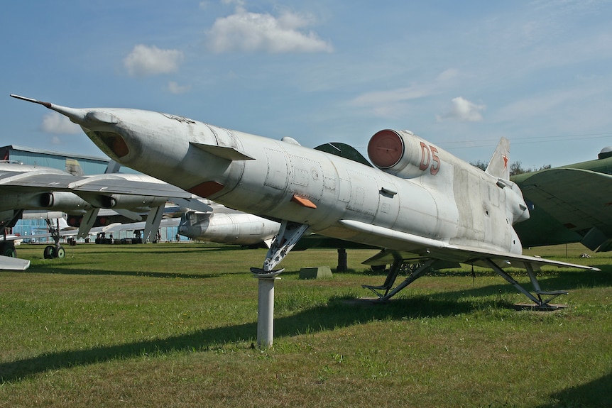 A large rocket-powered unpiloted drone sitting in a field.