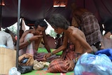 Rohingya men eat food at a confinement area for migrants